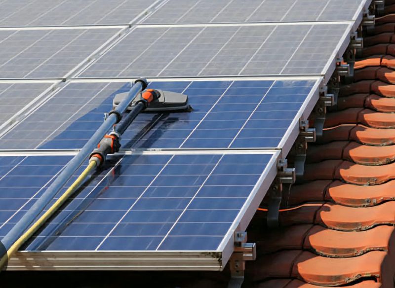Water-fed cleaning head moving across a solar array mounted on a terracotta tiled roof